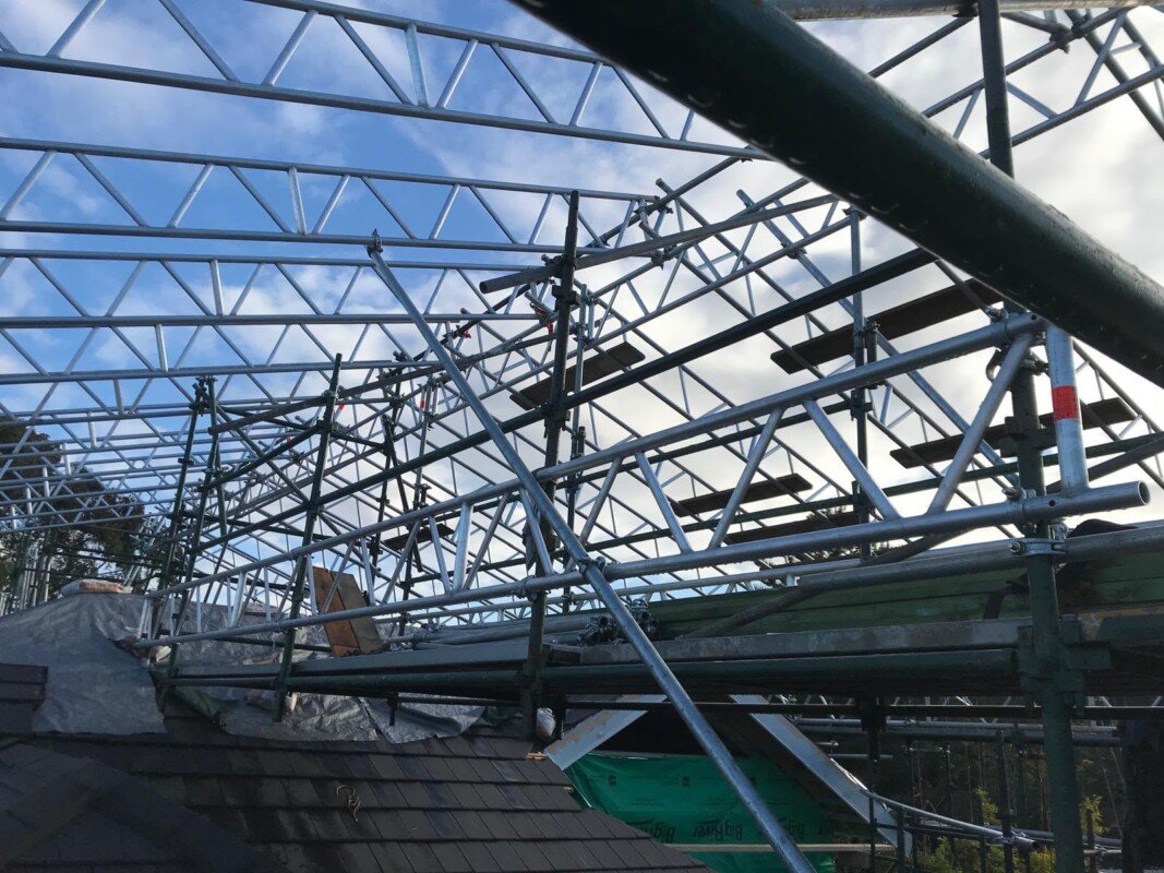 Temporary roof truss system under construction over an existing roof
